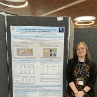Ellie stands next to her research poster