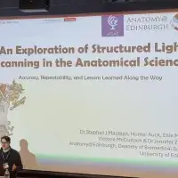 Dr Stephen Maclean standing in front of a large screen presenting his research