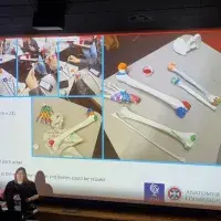 Dr Jennifer Paxton stands in front of a large screen showing colourful painted plastic bones