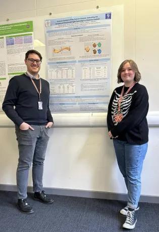 Stephen Maclean and Ellie Horne standing in front of the poster detailing her research findings. 