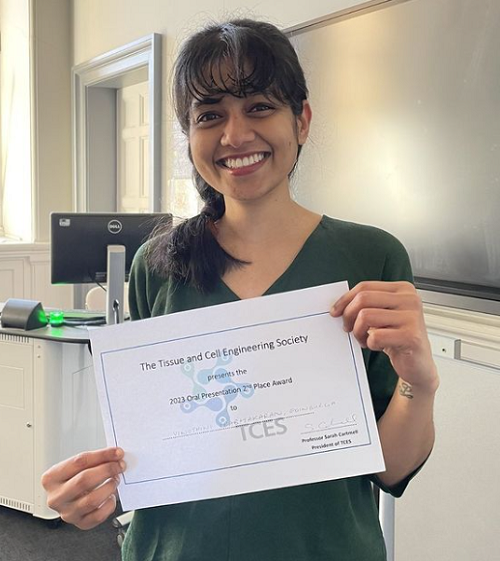 An image of Vinothini holding her award certificate